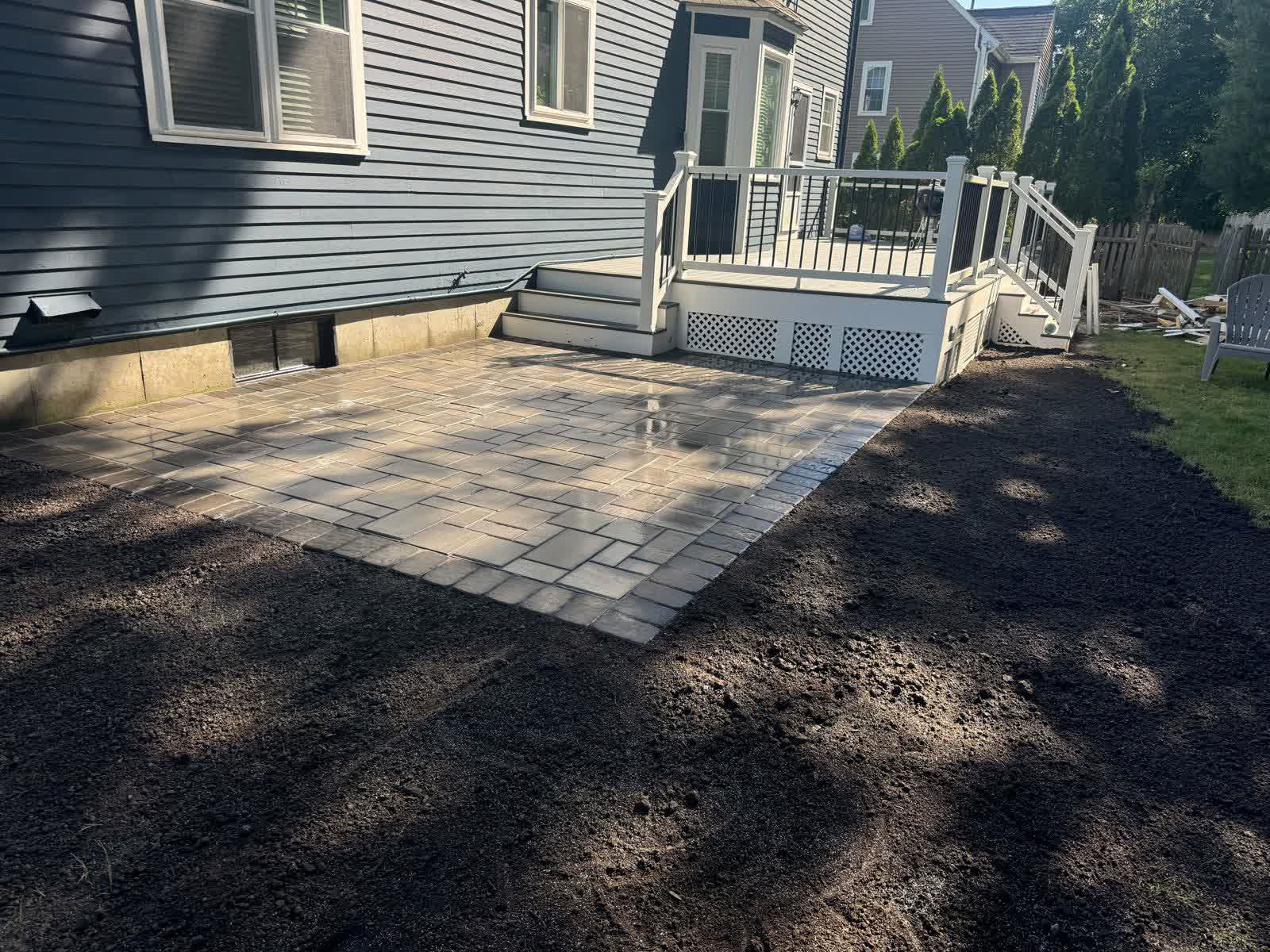 Backyard paver patio next to a deck