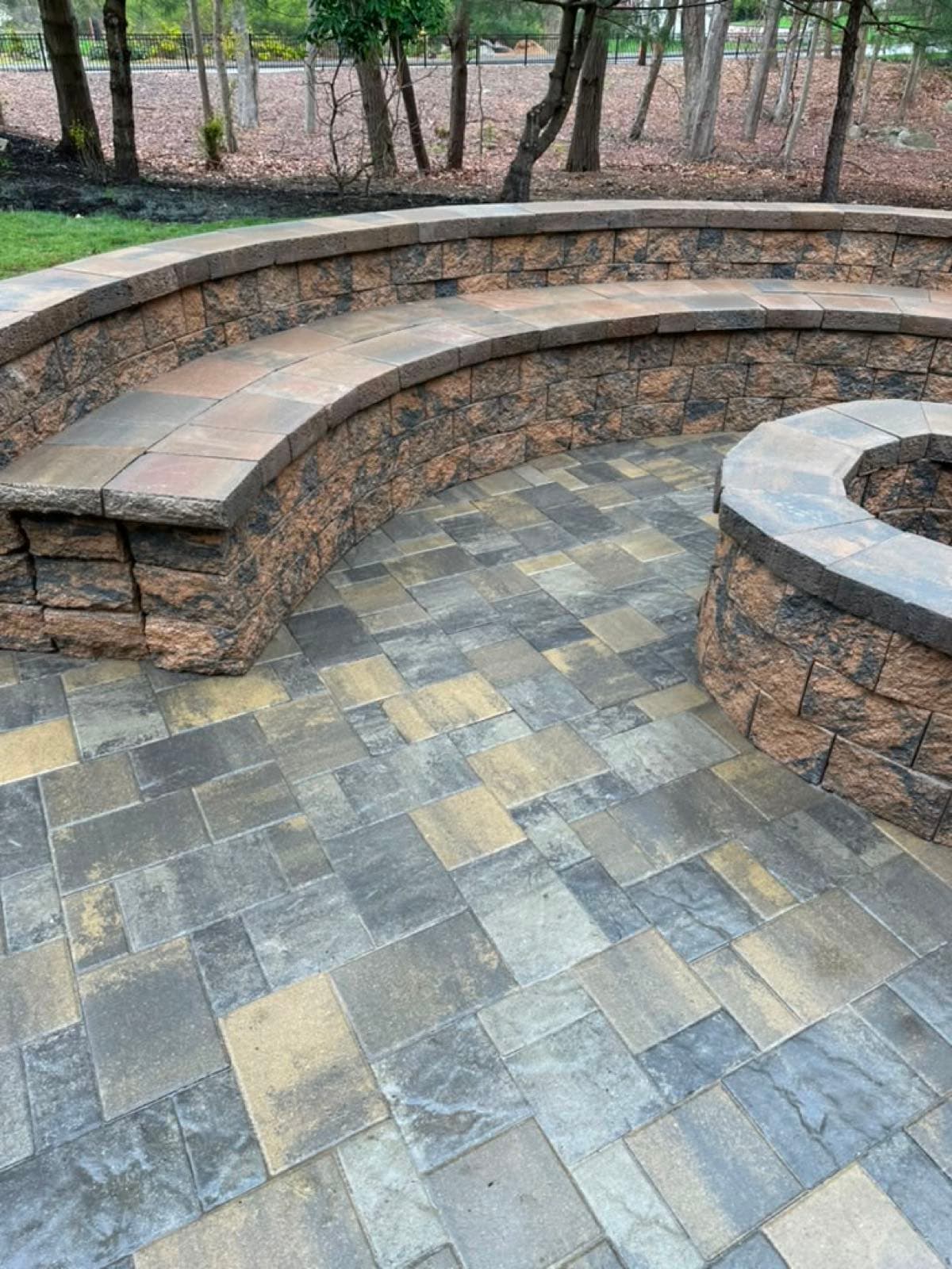 Paver patio with a stone fire pit and curved seating wall