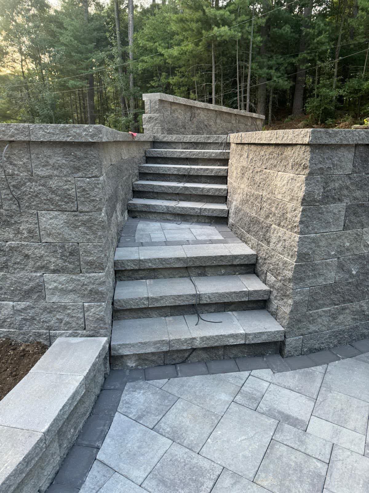Granite steps set between block retaining walls with a paver landing